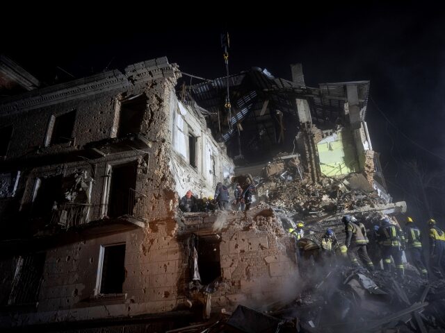 Ukrainian State Emergency Service firefighters clear the rubble at the building which was