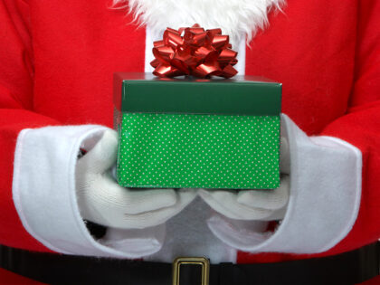 Santa holding a green box present with a red bow on - stock photo