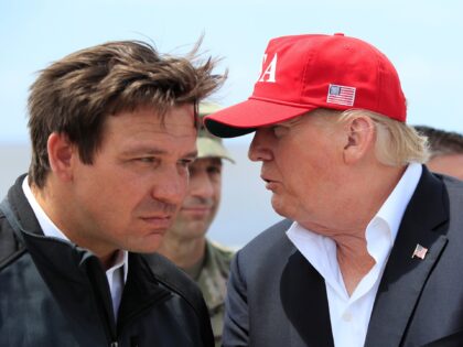 President Donald Trump talks to Florida Gov. Ron DeSantis, left, during a visit to Lake Ok