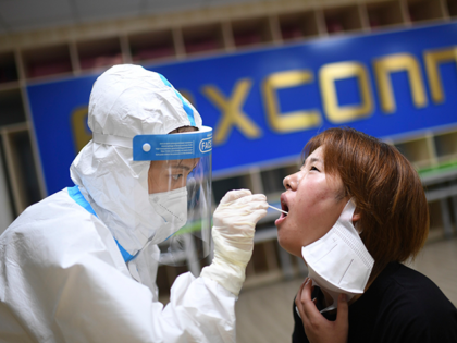 A medical worker takes a swab sample to test for COVID-19 from a worker at the Foxconn factory in Wuhan in central China's Hubei province Thursday, Aug. 5, 2021. Foxconn, the company that assembles Apple Inc.’s iPhones, has announced it is easing COVID-19 restrictions at its largest factory, in Zhengzhou, …