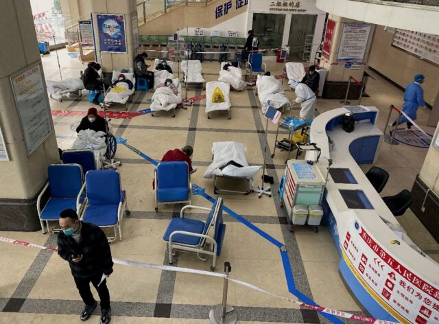 Covid-19 patients lie on hospital beds in a cordoned off area in the lobby of the Chongqin