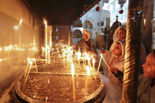 Pilgrims and tourists light candles inside the Church of the Nativity in the West Bank cit