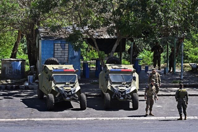 Soldiers stand guard during a raid against gang members in the Salvadoran city of Soyapang