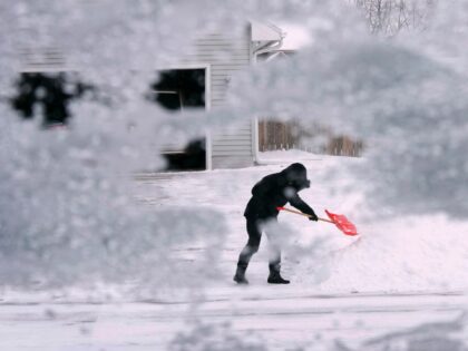 A local resident shovels snow off the end of a driveway, Thursday, Dec. 22, 2022, in Urban