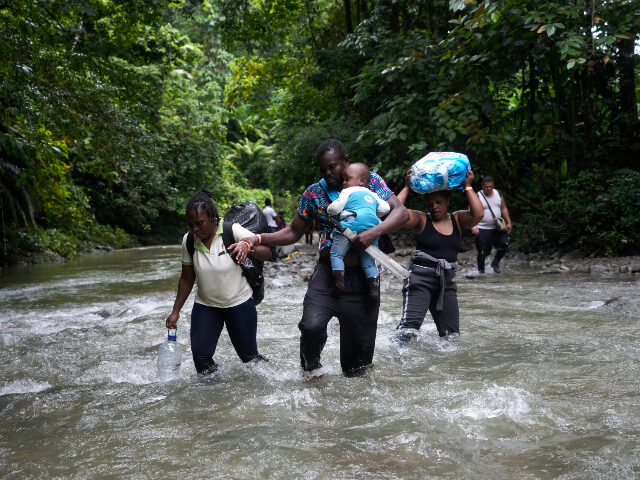 FILE - Haitian migrants wade through a river as they cross the Darien Gap, from Colombia i