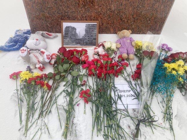 17 January 2023, Russia, Moskau: Flowers and a framed photo of the destroyed apartment bui
