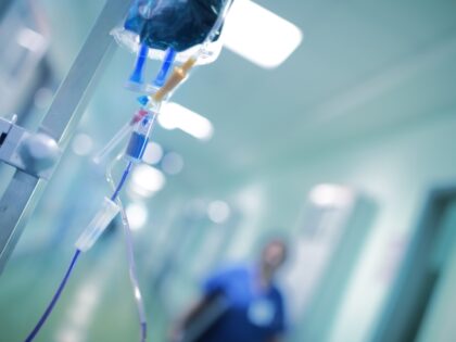 Intravenous drip with blue liquid ready to use on the background of walking around medical doctor, concept of mersy killing - stock photo
