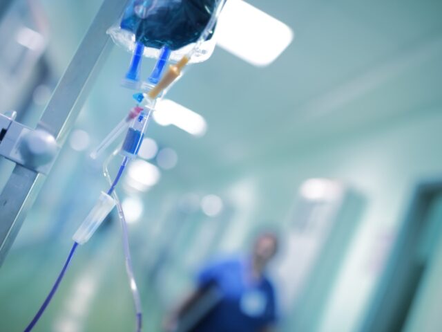 Intravenous drip with blue liquid ready to use on the background of walking around medical