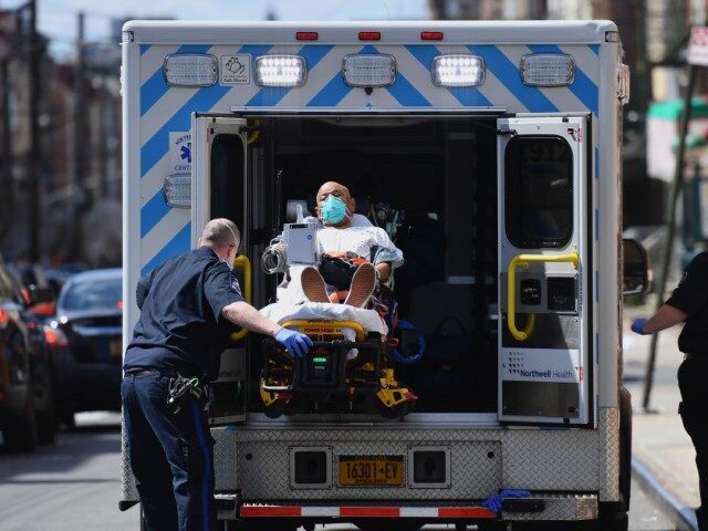 Paramedics transport a patient wearing a face mask to the emergency room entrance of the W