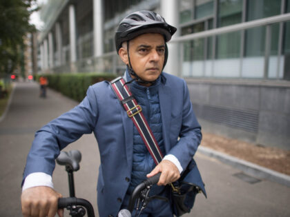 London mayor Sadiq Khan wheels his bicycle as he arrives at City Hall after he urged minis