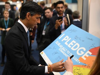 Britain's Chancellor of the Exchequer Rishi Sunak signs his name on a pledge to be an ally to the LGBT+ community at their stand on the second day of the annual Conservative Party Conference being held at the Manchester Central convention centre in Manchester, northwest England, on October 4, 2021. …