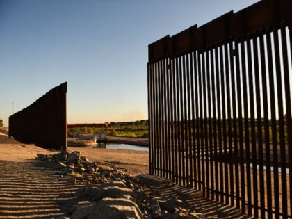 The sun sets behind a gap along the border wall at the Morelos Dam between the US and Mexico in Yuma, Arizona on May 31, 2022. - The stream of impoverished humans flowing into the United States via Mexico runs through the country's public discourse, dividing its politics and coloring …