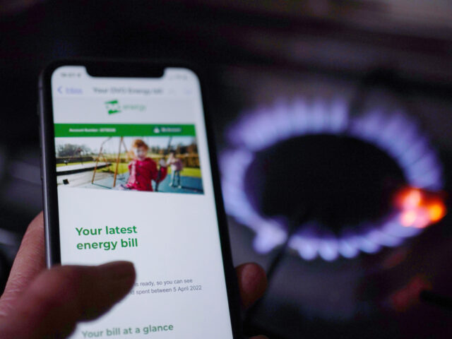 A general view of a household energy bill displayed on a mobile phone held next to a gas h