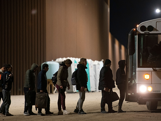 Asylum-seekers board a bus after being processed by US Customs and Border Patrol agents at