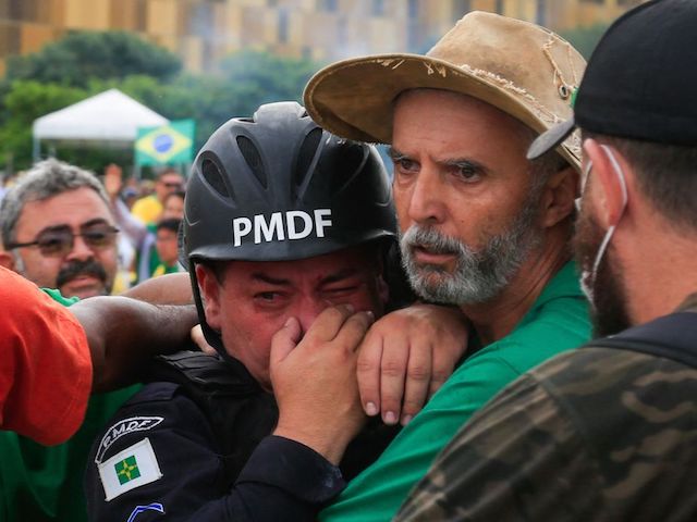 Supporters of Brazilian former President Jair Bolsonaro assist a Military Police officer during clashes after an invasion to Planalto Presidential Palace in Brasilia on January 8, 2023. - Hundreds of supporters of Brazil's far-right ex-president Jair Bolsonaro broke through police barricades and stormed into Congress, the presidential palace and the Supreme Court Sunday, in a dramatic protest against President Luiz Inacio Lula da Silva's inauguration last week. (Photo by Sergio Lima / AFP) (Photo by SERGIO LIMA/AFP via Getty Images)