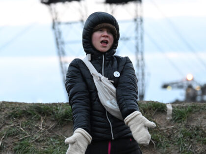 dpatop - 15 January 2023, North Rhine-Westphalia, Erkelenz: Climate activist Greta Thunberg (r) stands between Keyenberg and Lützerath under police guard on the edge of the open pit mine and dances. The energy company RWE wants to excavate the coal lying under Lützerath - for this purpose, the hamlet on …