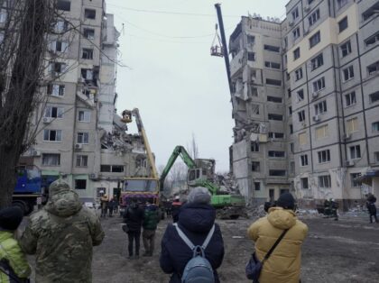 Local residents look at rescuers working on a residential building destroyed after a missile strike, in Dnipro on January 16, 2023, amid the Russian invasion of Ukraine. - According to State Emergency Service report, as of 1:00 pm on December 16, 40 people died, including 6 children; 75 people got …