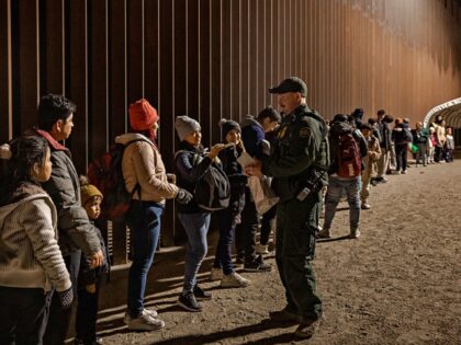 YUMA, ARIZONA - DECEMBER 30: A U.S. Border Patrol agent checks for identification of immigrants as they wait to be processed by the U.S. Border Patrol after crossing the border from Mexico on December 30, 2022 in Yuma, Arizona. (Photo by Qian Weizhong/VCG via Getty Images)