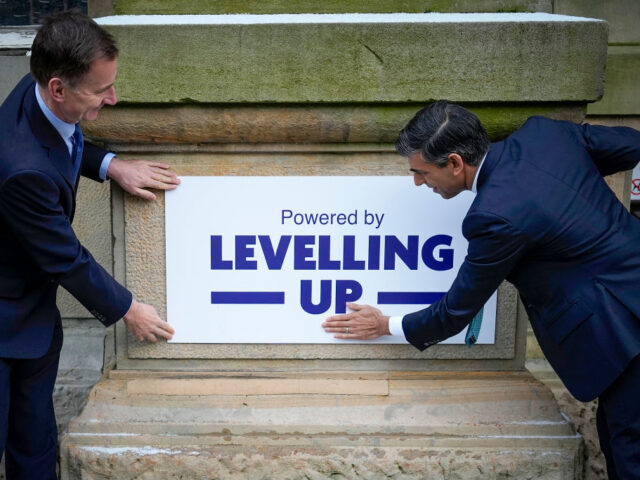 ACCRINGTON, ENGLAND - JANUARY 19: Prime Minister Rishi Sunak (R) and Chancellor Jeremy Hunt fix a 'Powered By Levelling Up' sign on to Accrington Market Hall during a visit on January 19, 2023 in Accrington, United Kingdom. Rishi Sunak visits community projects in Lancashire and County Durham to announce a …
