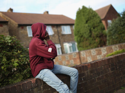 LONGFORD, ENGLAND - OCTOBER 14: A young asylum seeker checks his phone while sitting on a