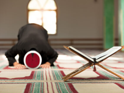 Young Imam praying inside of beautiful mosque.