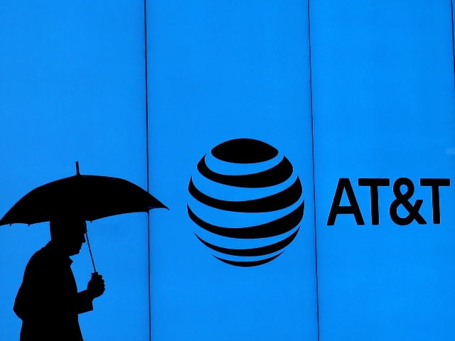 Man with umbrella stands in front of AT&T logo