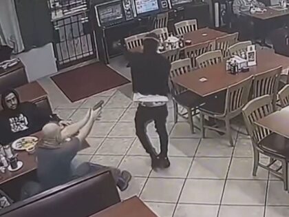 A customer in a Houston taqueria (seated) shoots and kills an armed robbery suspect. (Houston Police Department Video Screenshot)