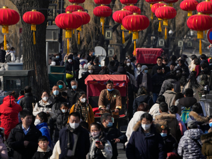A trishaw driver wades through a crowded street at the frozen Houhai Lake in Beijing, Monday, Jan. 30, 2023. The outlook for the global economy is growing slightly brighter as China eases its zero-COVID policies and the world shows surprising resilience in the face of high inflation, elevated interest rates …