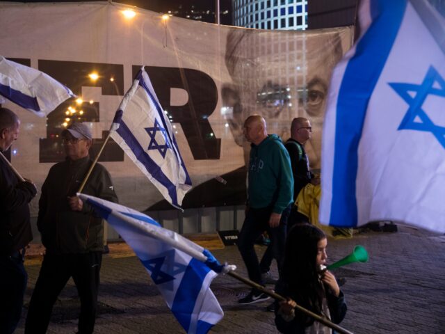 TEL AVIV, ISRAEL - JANUARY 28: Israelis hold the Israeli flag as they are walking by a pll