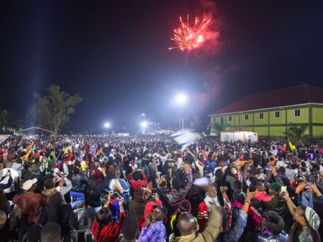 Fireworks light up the sky as people react while they celebrate after counting down to the