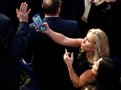 WASHINGTON, DC - JANUARY 06: U.S. Rep.-elect Marjorie Taylor Greene (R-GA) offers a phone with the initials "DT" to Rep.-elect Matt Rosendale (R-MT) in the House Chamber during the fourth day of voting for Speaker of the House at the U.S. Capitol Building on January 06, 2023 in Washington, DC. …