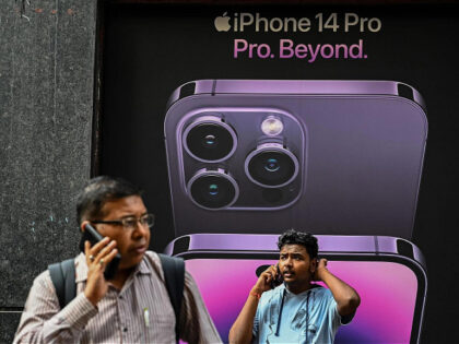 Men talk on their mobile phones in front of an iphone 14 advertisement, in Kolkata on Sept
