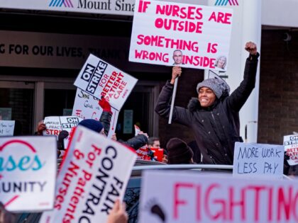 A supporter stands through the sunroof of a passing vehicle in front of Mt. Sinai Hospital in the Manhattan borough of New York, Monday, Jan. 9, 2023, as nurses stage a strike following the breakdown of negotiations with the hospital hours earlier. Thousands of nurses have gone on strike at …
