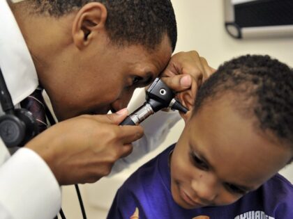 Jacob Edwards, R, a resident-in-training physician, examines LeySean Blair, 5, at the Chil