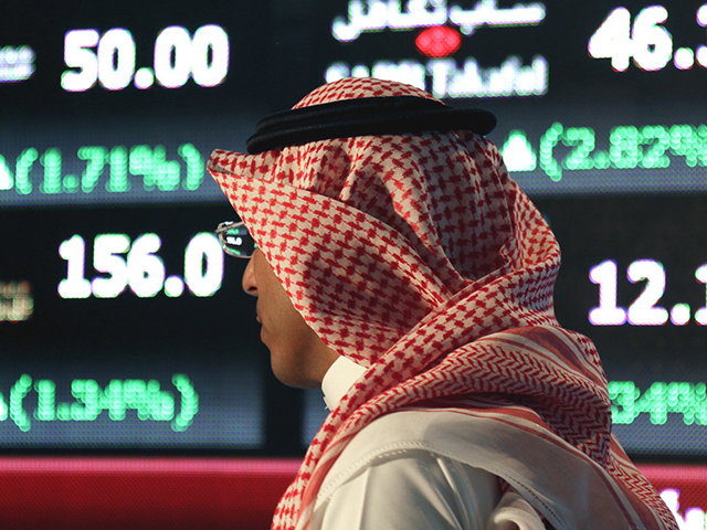 In this June 15, 2015, file photo, a Saudi man walks through the Tadawul stock exchange in Riyadh, Saudi Arabia. Saudi Arabia's National Commercial Bank said Sunday, Oct. 11, 2020, it will purchase rival lender Samba Financial Group in a deal valued at $14.8 billion, creating what would become the …