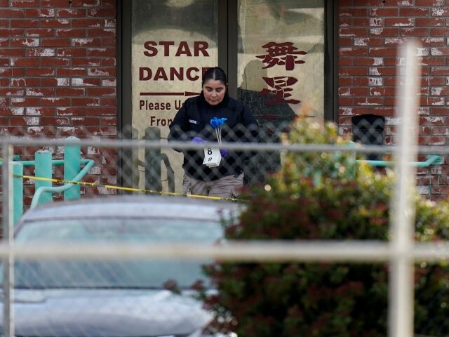 An investigator carries markers outside Star Dance Studio in Monterey Park, Calif., Sunday