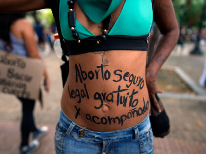 A woman walks with the message written on her belly that reads in Spanish "Safe, legal, free and accompanied abortion," during the Global Day of Action for access to legal, safe and free abortion, at a square in Caracas, Venezuela, Tuesday, Sept. 28, 2021. (AP Photo/Ariana Cubillos)