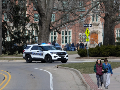 A police vehicle blocks a road as students walk on the Michigan State University campus in East Lansing, Mich., Tuesday, Feb. 14, 2023. A gunman killed several people and wounded others at Michigan State University. Police said early Tuesday that the shooter eventually killed himself. (AP Photo/Paul Sancya)