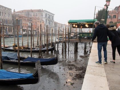 People look at gondolas docked along a canal during a low tide in Venice, Italy, Tuesday, Feb. 21, 2023. Some ofVenice's secondary canals have practically dried up lately due a prolonged spell of low tides linked to a lingering high-pressure weather system. (AP Photo/Luigi Costantini)