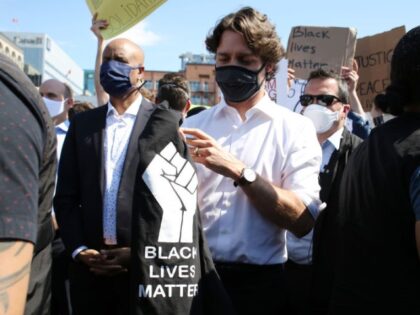 Canadian Prime Minister Justin Trudeau (C) holds a t-shirt he was handed while taking part in a Black Lives Matter protest on Parliament Hill June 5, 2020 in Ottawa, Canada. - Canadian Prime Minister Justin Trudeau appeared at a loss for words on June 2, pausing for 20 seconds when …
