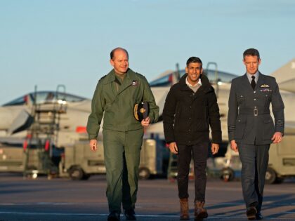 Britain's Prime Minister Rishi Sunak (C) walks with Britain's Air Chief Marshal Mike Wigston (L) and RAF Coningsby Station Commander Billy Cooper, as they pass Typhoon fighter jets, during his visit to Royal Air Force RAF Coningsby, near Lincoln, eastern England, on December 9, 2022, following the announcement that Britain …