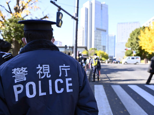 TOKYO, JAPAN - DECEMBER 16 : A police officer stands guard as people gather outside Japanese Prime Minister Fumio Kishida's office while holding placards denouncing the violation of Article 9 of the Japanese Constitution in Tokyo, Japan on December 16, 2022. The protesters also show their opposition to the increase …
