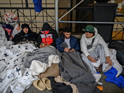 Migrants camp outside a hotel where they had previously been housed, as they resist effort