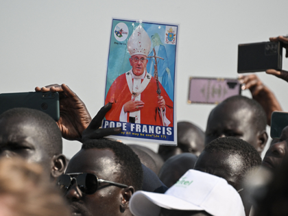 A man holds a picture of Pope Francis as a crowd gathers to welcome him upon his arrival a