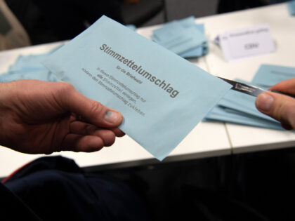 12 February 2023, Berlin: An election worker opens the ballot envelope of a postal voter i