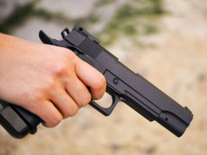 Realistic black airsoft gun in person hand. Close-up
