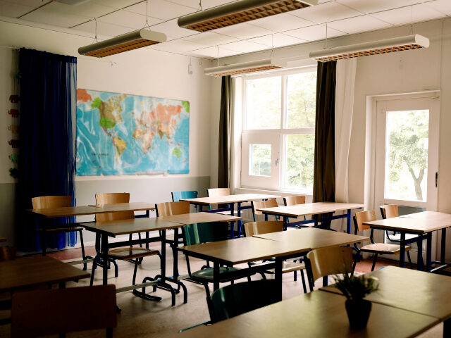 Desks and chairs arranged in classroom at high school - stock photo