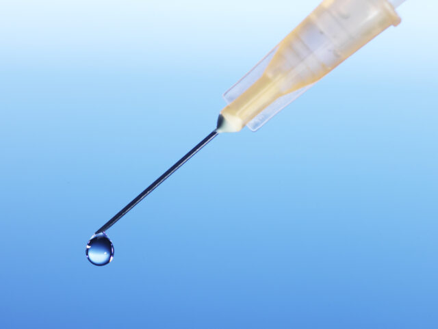 Detail / Close up of medical syringe, Macro photography, needle only, with a droplet