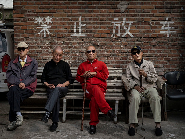 Retired Chinese men sit on a bench outside an apartment complex for pensioners on the seco