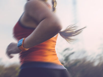 Woman running outdoor using a smart watch to track data.